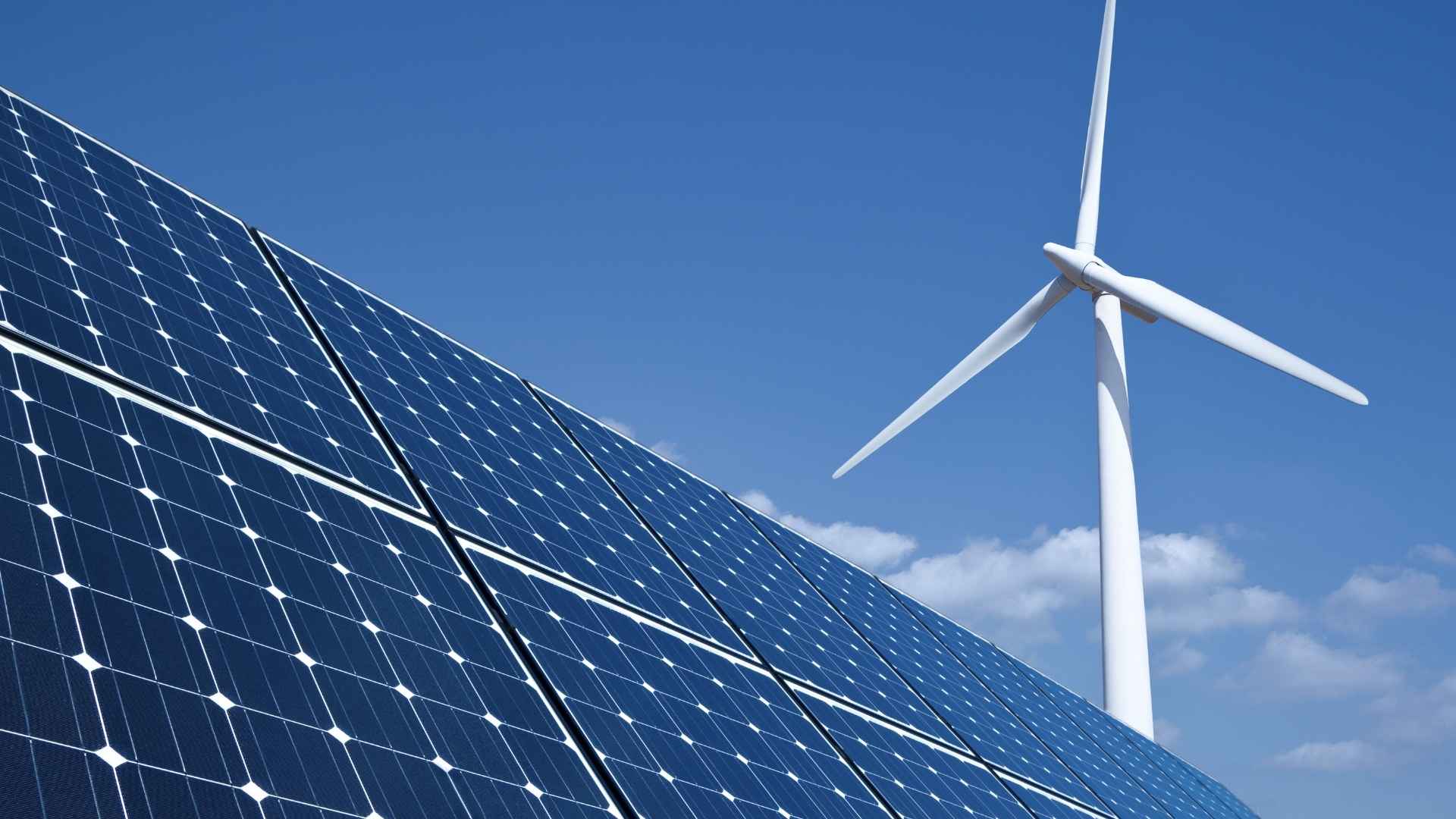Solar panels and a wind turbine against a blue sky