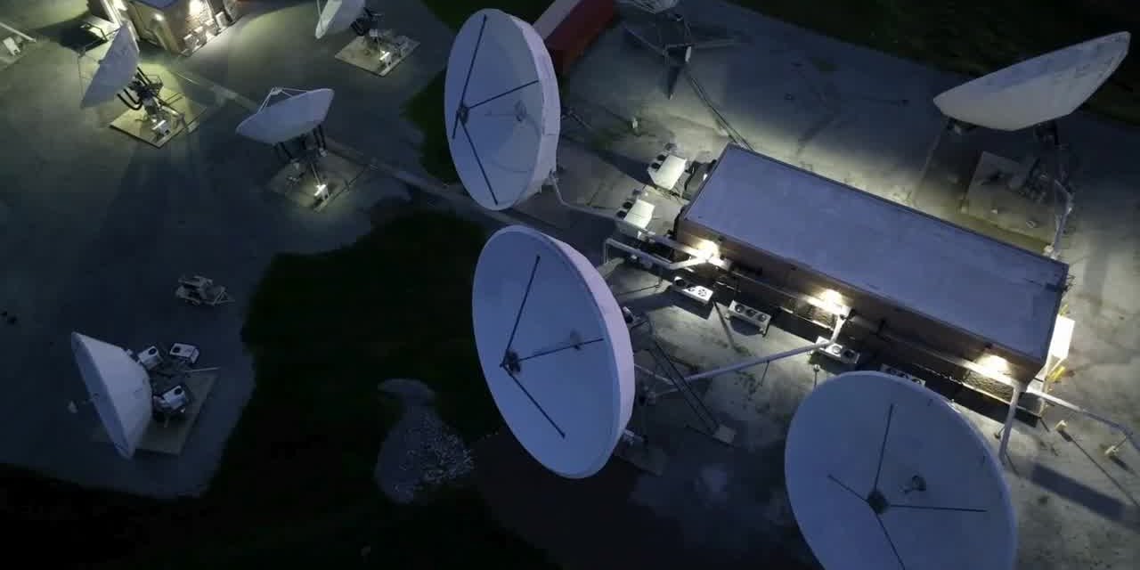 Satellite dishes at a ground station at night - communications electronics manufacturing UK